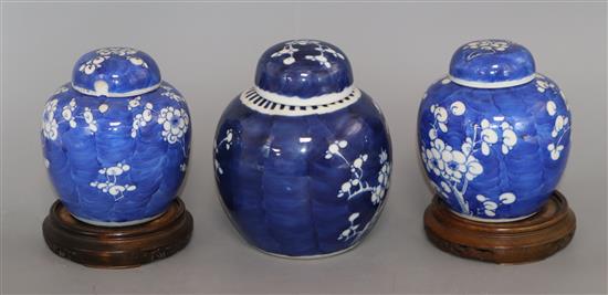 A Chinese ginger jar and cover decorated with prunus and a similar smaller pair of ginger jars on hardwood bases